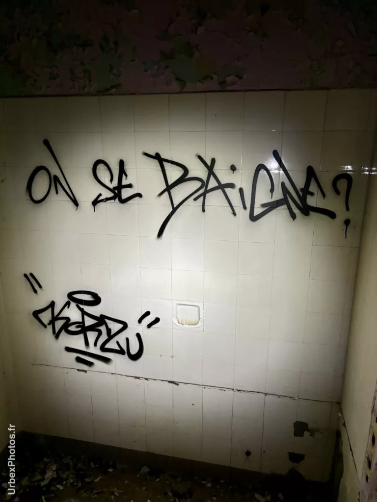 Message "On se baigne ?" sur un mur carrelé