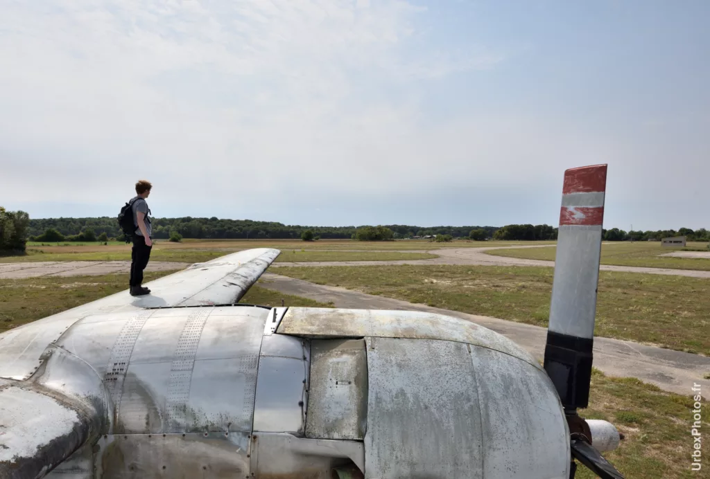 Photo urbex d'un homme debout sur l'aile gauche du Lockheed P2V-7 Neptune dans le Grand Est