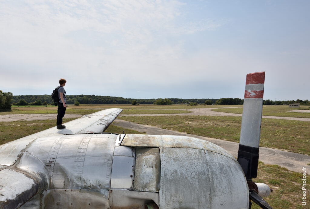 Photo urbex d'un homme debout sur l'aile gauche du Lockheed P2V-7 Neptune dans le Grand Est