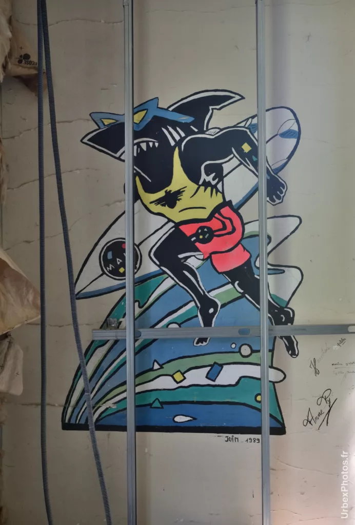 Photo urbex en gros plan du dessin du requin humanoïde, datant de juin 1989, dans l'Hôtel Nougaro en Lorraine