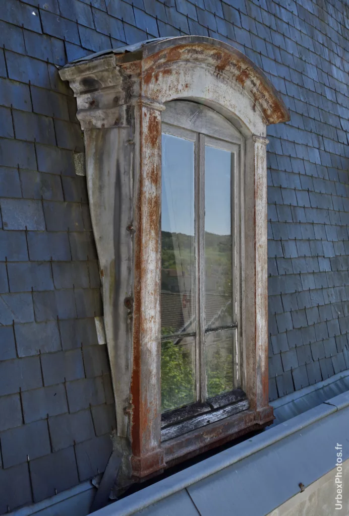 Photo urbex d'une fenêtre en chien-assis, depuis l'extérieur, de l'Hôtel Nougaro en Lorraine