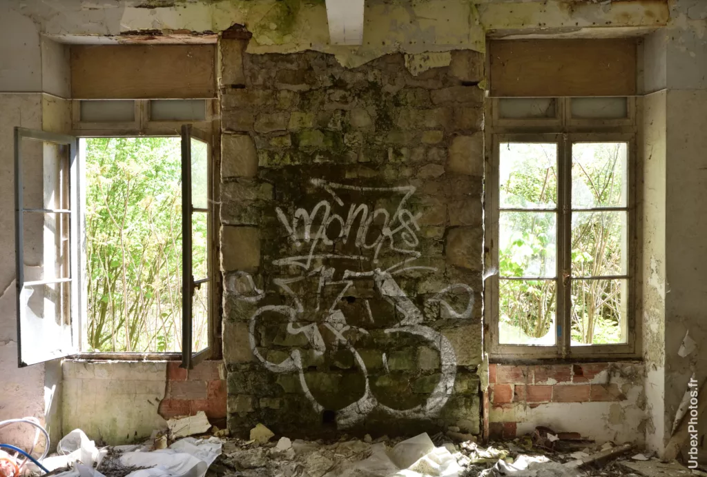 Des fenêtres jumelles séparées par un graffiti