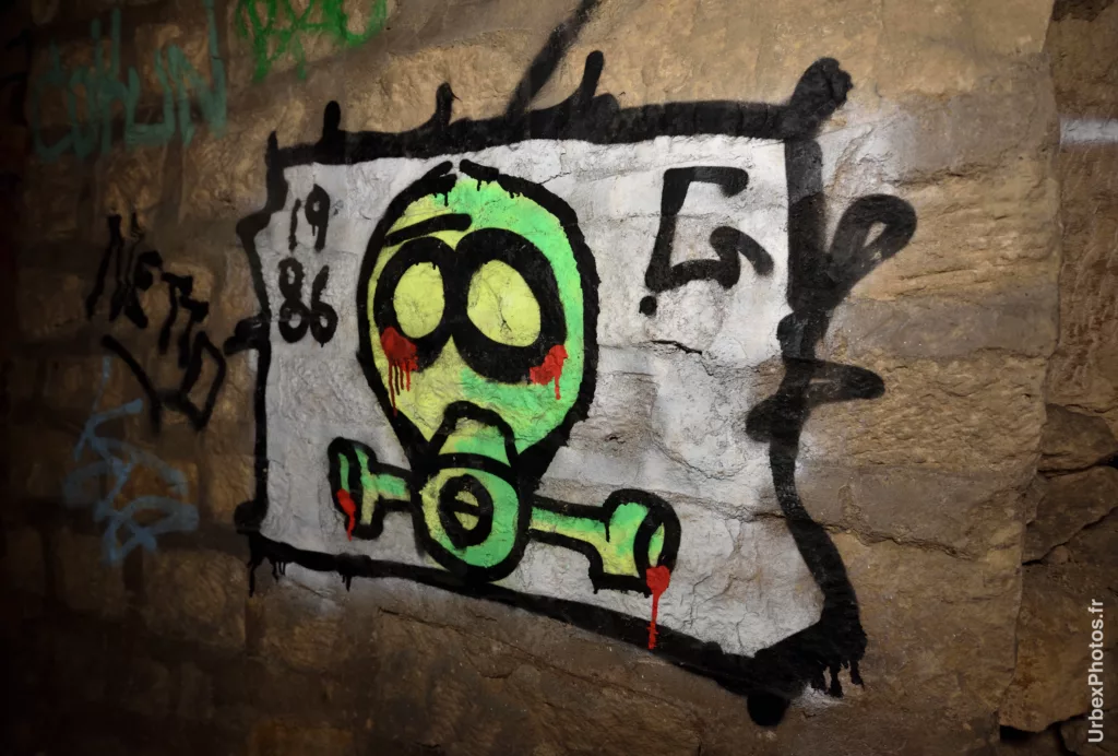 Photo urbex du graffiti d'un masque de liquidateur dans les catacombes interdites de Paris